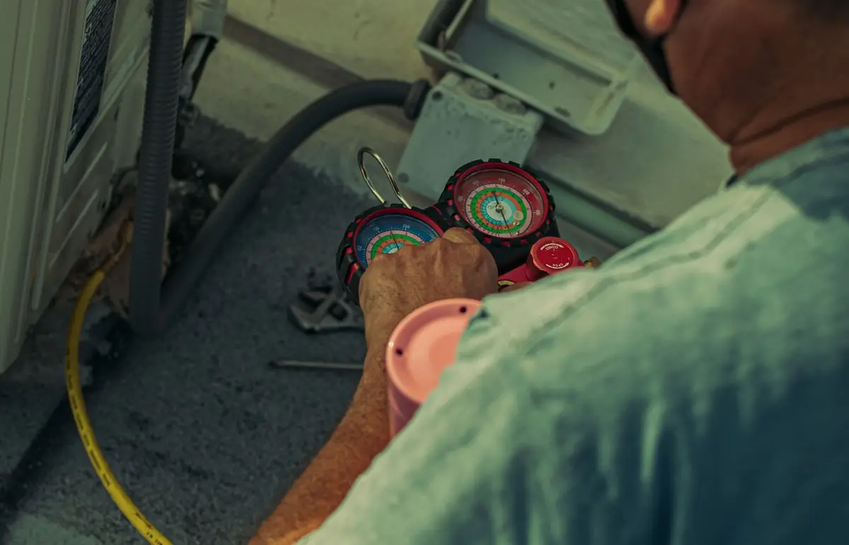 HVAC technician checking refrigerant gauges on an air conditioning unit